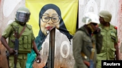 Полицейские на фоне повреждённого протестующими плаката Самии Хасан Сулуху