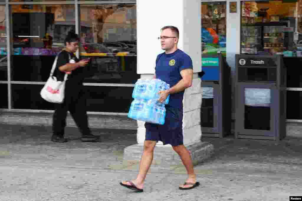 Muškarac iznosi pakete flaširane vode iz prodavnice nakon što su vlasti upozorile na mogući cunami, u Honoluluu, Havaji, SAD, 29. jula 2025.