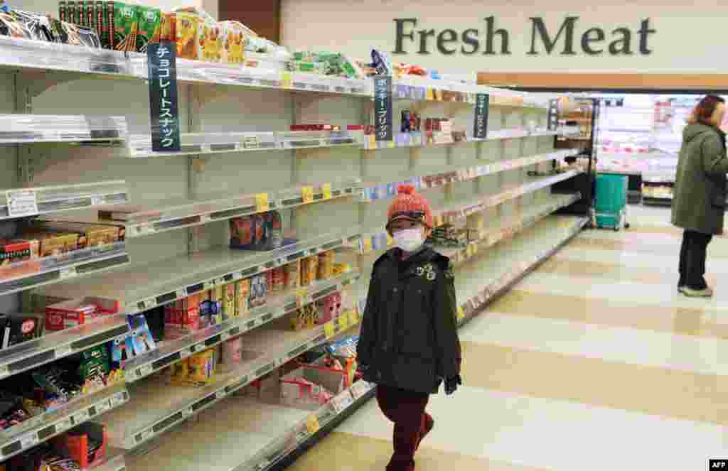 Dečak pod zaštitnom maskom prolazi pored praznih rafova u prodavnici u gradu Akita na severozapadu Japana 15. marta 2011. godine, nakon što su stanovnici panično pokupovali osnovne namirnice širom zemlje nakon cunamija.