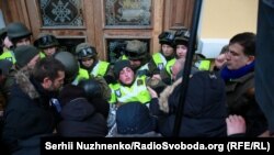 Міхеїл Саакашвілі (праворуч) спостерігає, як мітингувальники, яких він закликав йти до Жовтневого палацу, під час штурму будівлі виривають бійця Нацгвардії зі строю перед центральним входом до палацу. Київ, 17 грудня 2017 року