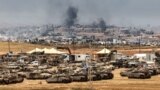 This picture taken from a position in southern Israel on the border with the Gaza Strip shows Israeli tanks and bulldozers deployed as smoke billows over destroyed buildings in Gaza during Israeli bombardment on May 17, 2025.