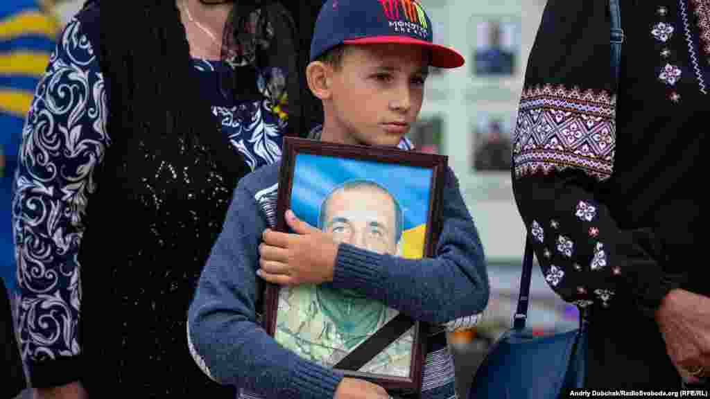 Ребенок обнимает фотографию отца, погибшего в "Иловайском котле". Киев, траурные мероприятия памяти погибших украинских солдат около Михайловской церкви в центре Киева