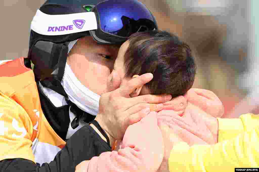 Сноубордист Південної Кореї Кім Юн-хо цілує свою доньку після закінчення кваліфікаційного заїзду в чоловічому кросі