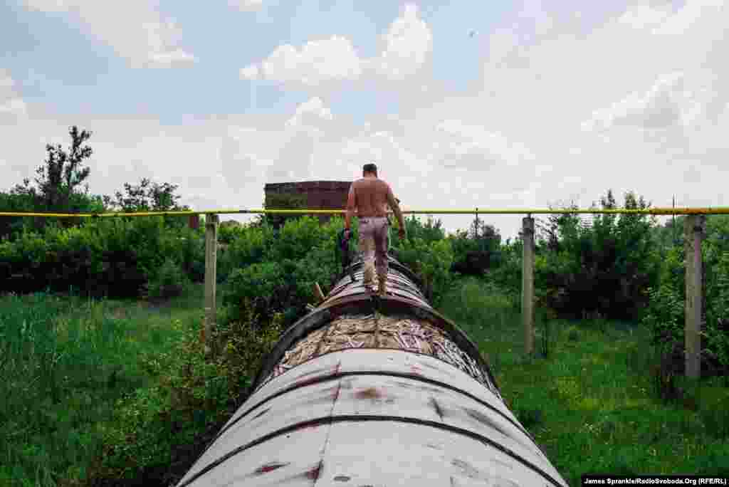 Командир 17-го батальйону прогулюється вздовж водопроводу, що був пошкоджений мінометом декілька тижнів тому. До того, як отвір полагодили, люди могли приймати душ під струменем води з нього