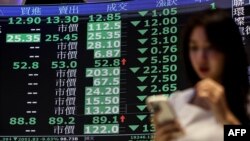 Žena pored ploče s prosječnim cijenama dionica na Tajvanskoj berzi u Tajpeju 7. aprila 2025.