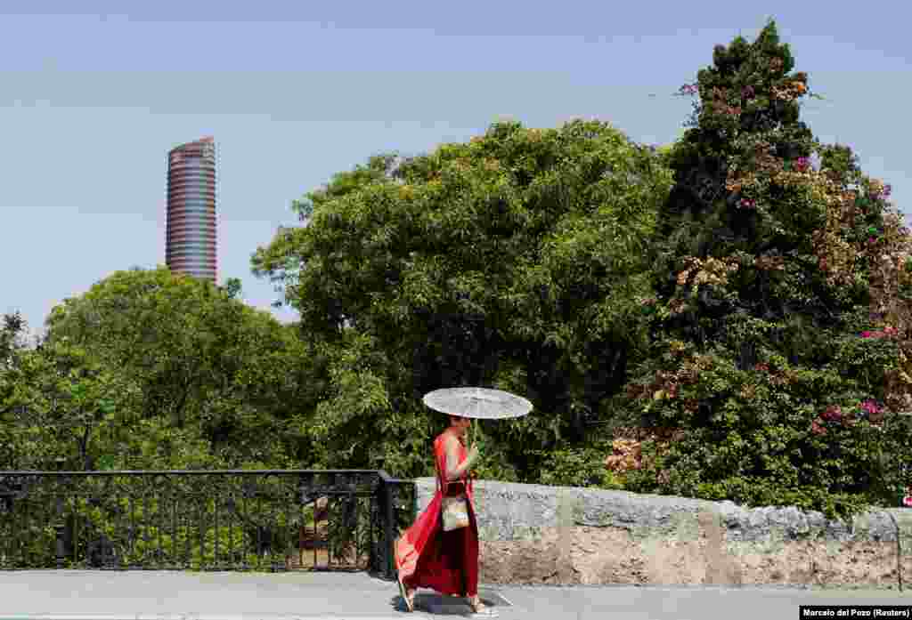 Një grua duke e mbrojtur veten nga dielli me një ombrellë, në Sevillë, Spanjë, më 29 qershor.