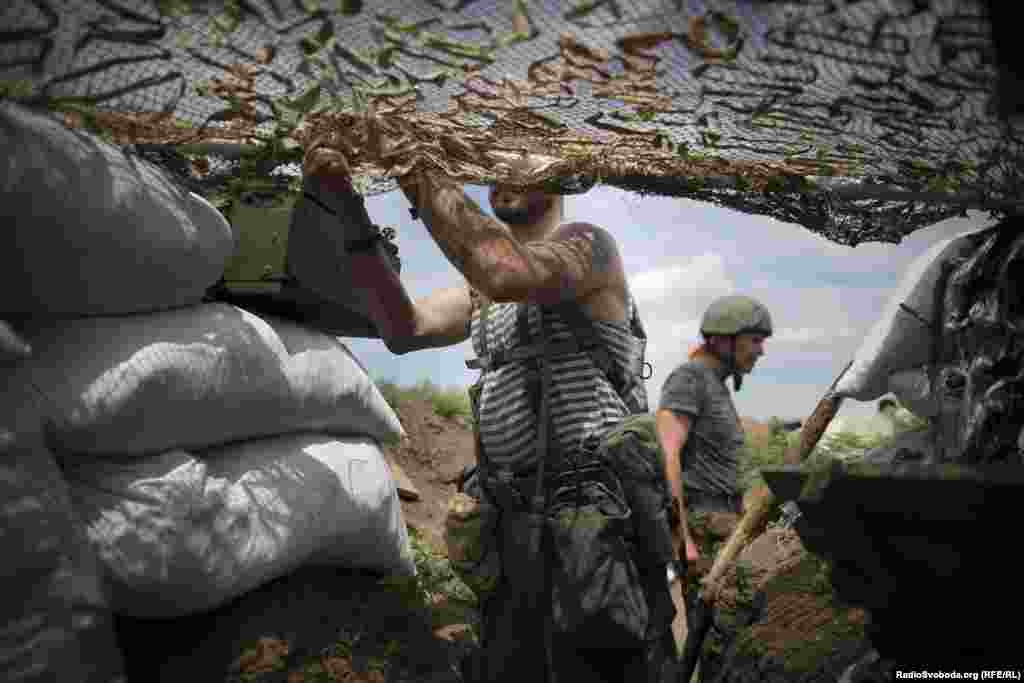 Один из бойцов батальона "Донбасс" с позывным "Гюнтер" маскирует окопы