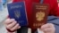 Женщина держит украинский и российский паспорта у офиса Федеральной миграционной службы России, открытого в Симферополе после аннексии Крыма, 7 апреля 2014 года. Архивное фото