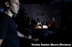 Люди в кафе изучают меню под светом фонарика мобильного телефона