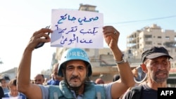 Predstavnik medija drži transparent na kojem na arapskom piše "gladni novinar piše izvještaj o gladnima", u gradu Gazi 19. jula 2025.