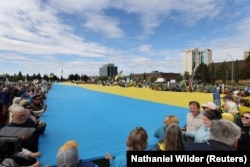 Демонстранты держат украинский флаг после того, как президент США Дональд Трамп заявил, что он и президент России Владимир Путин не достигли соглашения в ходе встречи, Аляска, 15 августа 2025 года