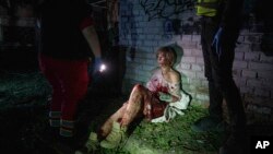 დაშავებული ქალი ზის თავის სახლთან, რომელიც დაზიანდა რუსეთის საჰაერო თავდასხმის შედეგად, კიევის საცხოვრებელ უბანში. 24 აპრილი, 2025.