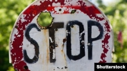 Пробитый пулями и осколками дорожный знак возле въезда в Донецк. Украина, июль 2016 года