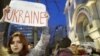 Učesnica protesta nosi transparent sa porukom "Stojimo sa Ukrajinom"