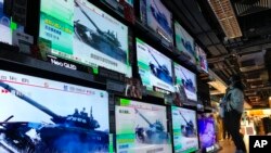 Žena u prodavnici gleda na ekrane koji prenose vijesti o napadu Rusije na Ukrajinu, Hong Kong, 24. februar 2022.