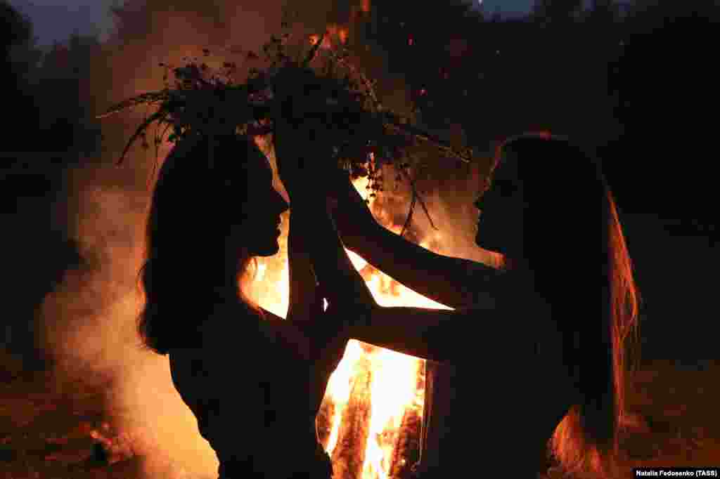 Дівчата одягають на голову вінки біля купальського  багаття. Під час святкування Івана Купала на березі річки Прип'ять. Білорусь, Гомельська область, 6 липня