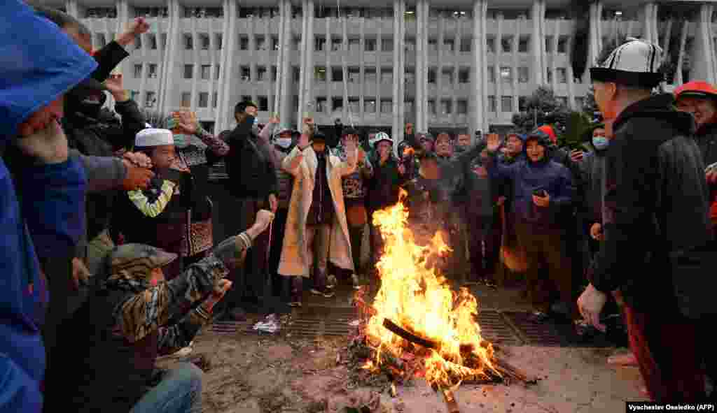 Ljudi koji prosvjeduju protiv rezultata parlamentarnih glasanja okupljaju se oko vatre zapaljene ispred Bijele kuće u Biškeku.