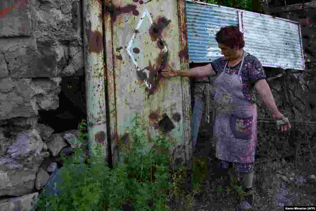 Žena u armenskom selu Aygepar pokazuje kako je kapija njenog dvorišts oštećena granatiranjem.&nbsp;