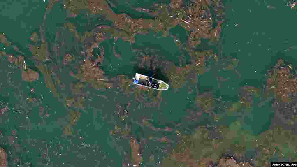 Snimak iz zraka prikazuje čovjeka kako vesla čamcem kroz blato i otpad nakon što su razorne poplave i klizišta onečistili Jablaničko jezero u blizini Ostrožca, u Bosni i Hercegovini.