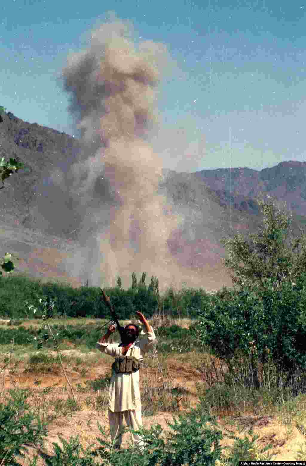 Mudžahedinski borac prati kretanja na nebu nakon vazdušnog napada. Kako su uslovi postajali sve rizičniji za strane novinare unutar Afganistana (godine 1984. sovjetski diplomata je obećao da će bilo koji novinar uhvaćen s mudžahedini biti ubijen), Washington je finansirao kontroverzni program unutar kojeg su se afganistanskim pobunjenicima poslale kamere.