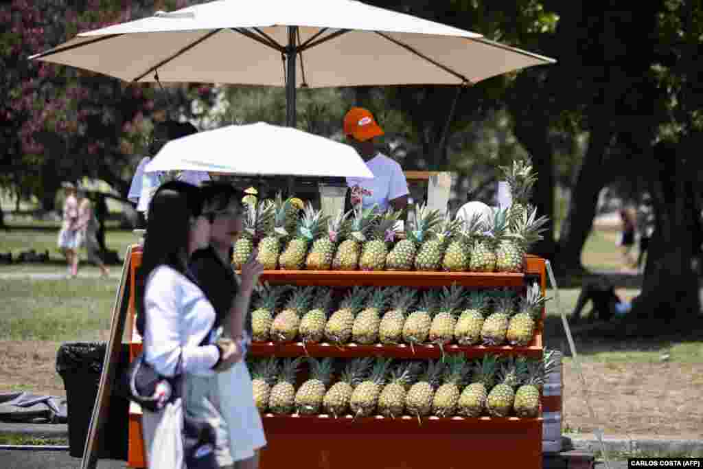 Dy gra duke përdorur një ombrellë për t'u mbrojtur nga dielli përvëlues, në Lisbonë, Portugali, më 29 qershor.