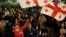 Демонстранти развяват грузински знамена, докато участват в протест по повод първата годишнина от оспорваните парламентарни избори. Снимката е от 26 октомври 2025 г.