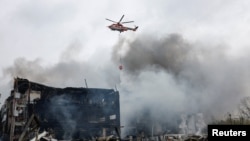 Вертолет пытается потушить пожар в Киеве, возникший в результате российского воздушного удара. 25 октября 2025 года