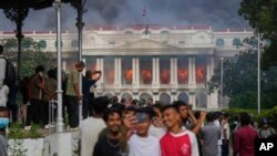 Протестиращи срещу решение на властите в Непал да ограничат достъпа до социалните мрежи си правят селфи на фона на горящия дворец Сингха Дурбар, който се използва от правителството и парламента на страната, 9 септември 2025 г.