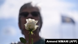 Rođaka nestale osobe drži ružu ispred spomen-obeležja posvećenog nestalim licima u Prištini 30. avgusta 2024. godine, povodom obeležavanja Međunarodnog dana žrtava prisilnih nestanaka.