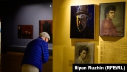 Посетител на изложбата "Картина извън картината" разглежда автопортрети на Иван Вукадинов.