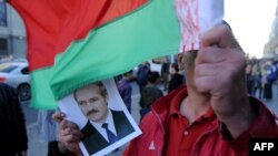 Чоловік тримає прапор Білорусі та портрет президента Білорусі Олександра Лукашенка під час опозиційного мітингу у центрі Мінська. 10 вересня 2015 року