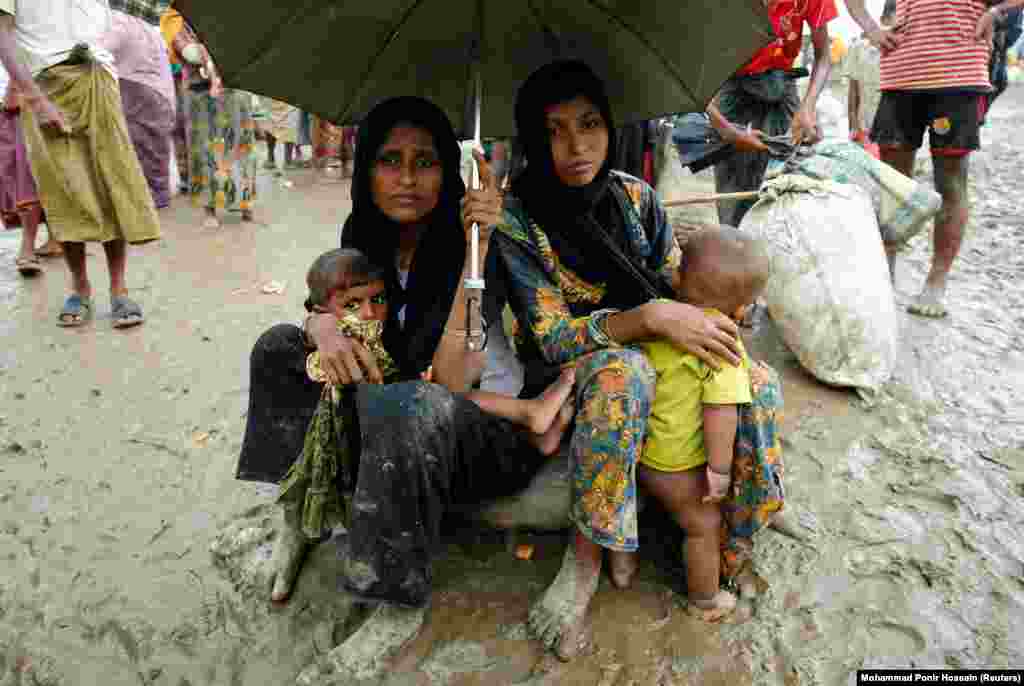 Беженцы рохинджа сидят со своими вещами во время сильного дождя после того, как они были задержаны пограничниками за незаконное пересечение Бангладеш.