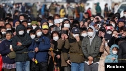 Толпа, собравшаяся на улице, пытается разглядеть церемонию передачи олимпийского огня. Токио, 20 марта