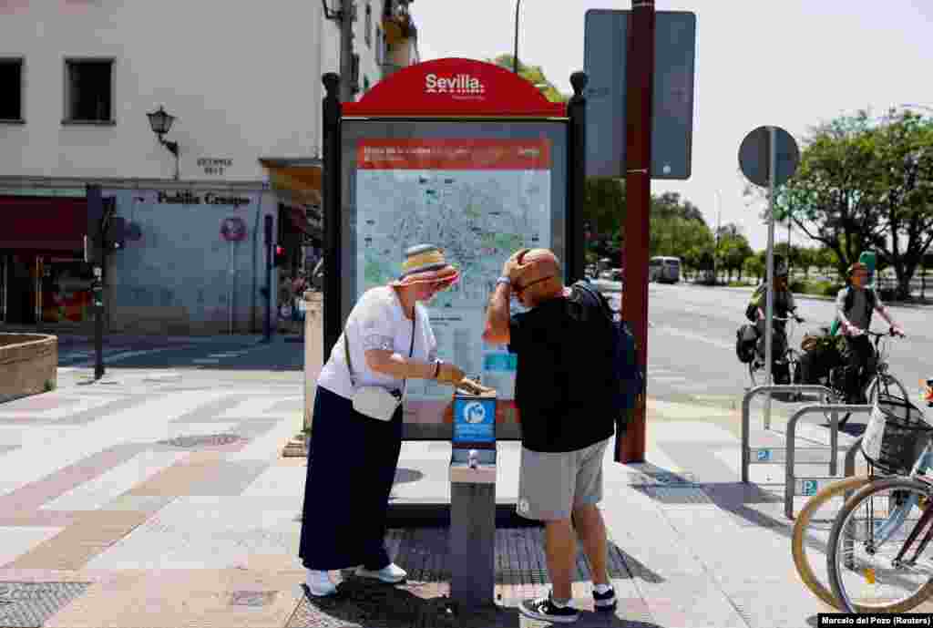 Një çift duke u freskuar me ujë nga një krua publik në Sevillë, më 29 qershor.