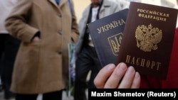 Женщина держит украинский и российский паспорта у офиса Федеральной миграционной службы России, где она получила российский паспорт от оккупационной власти. Симферополь 7 апреля 2014 года