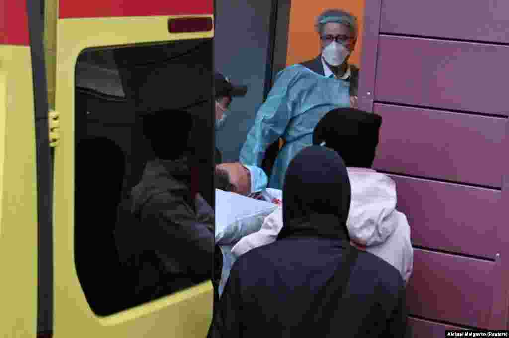 Медики в Омске несут российского оппозиционера Алексея Навального на носилках в машину «скорой помощи» по пути в аэропорт перед его эвакуацией в Германию, 22 августа 2020 года