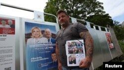 Glasač pored plakata Nacionalnog okupljanja, na dan izbora, 30. juni 2024.