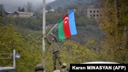ფოტო არქივიდან: აზერბაიჯანელი ჯარისკაცი ქალაქ ლაჩინში ბოძზე ამაგრებს აზერბაიჯანის სახელმწიფო დროშას. 2020 წლის 1 დეკემბერი