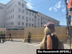 თამუნა კაკაურიძე შეჰყურებს თავისი სახლის ფანჯრებს, რომლის თავზეც ჩამოინგრა შენობის ნაწილი.