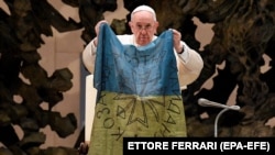 Папа Римський Франциск тримає прапор, який йому привезли з Бучі, під час його щотижневої загальної аудієнції. Ватикан, 6 квітня 2022 року 