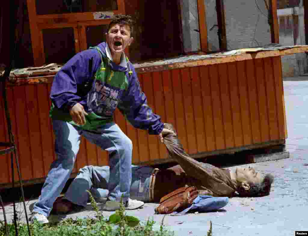 Čovjek traži pomoć za jednu od žrtava smrtonosne eksplozije, kakvih je dnevno bilo na hiljade.